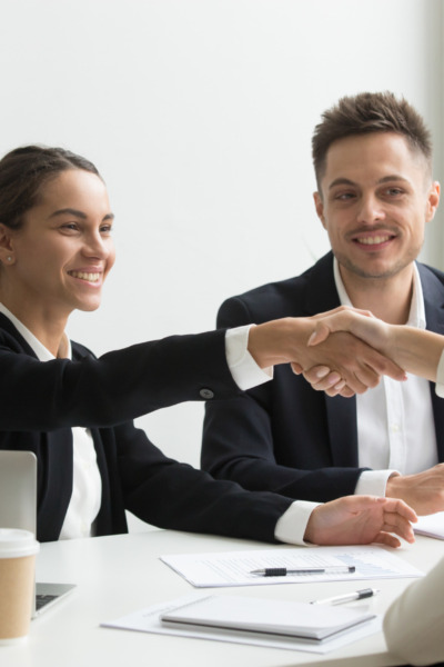 Smiling HR managers greeting female job applicant with handshake during recruiting or interview. Businesswoman making good first impression shaking hands of business partners. Partnership, cooperation