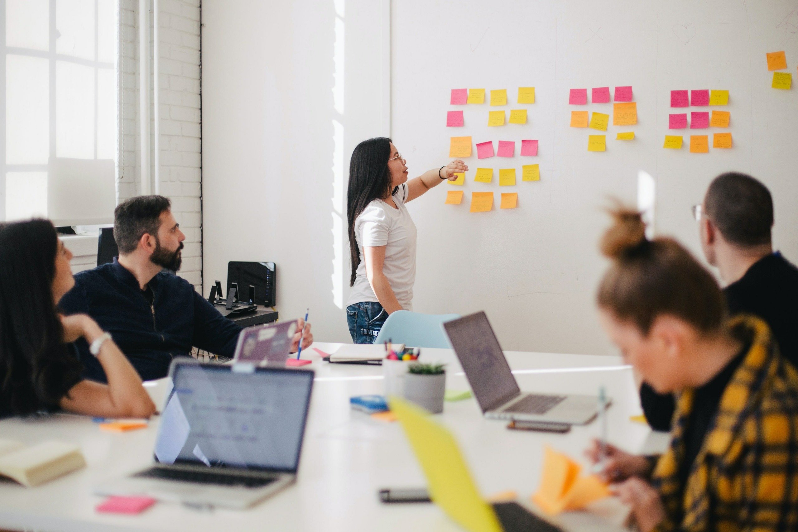 people in a meeting, woman pointing at whiteboard